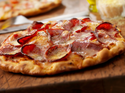 A pepperoni pizza presented on a wooden chopping board.